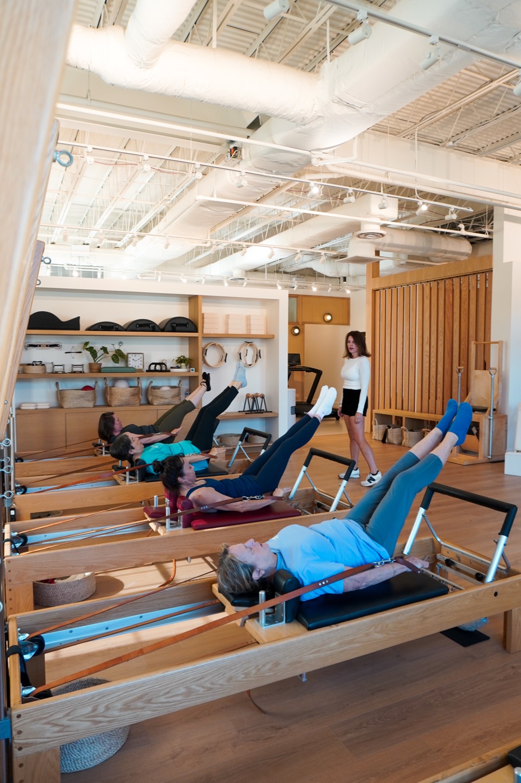 A Pilates class practicing with feet in reformer straps